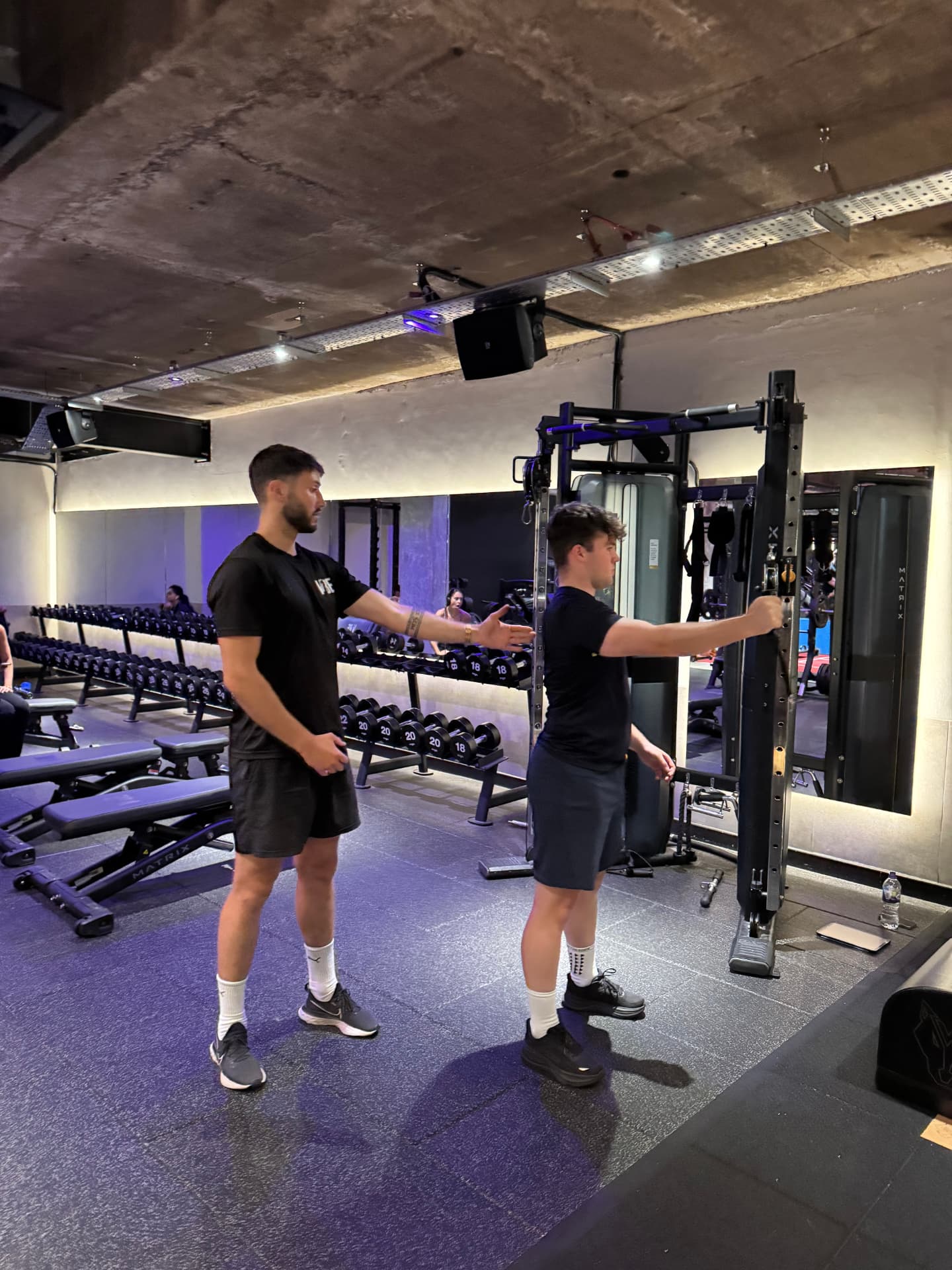 Coach cueing a client’s back position as they work through a cable exercise in a gym